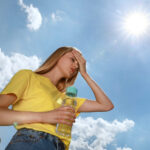 Woman,With,Bottle,Of,Water,Suffering,From,Heat,Stroke,Outdoors