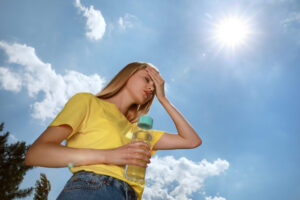 Woman,With,Bottle,Of,Water,Suffering,From,Heat,Stroke,Outdoors